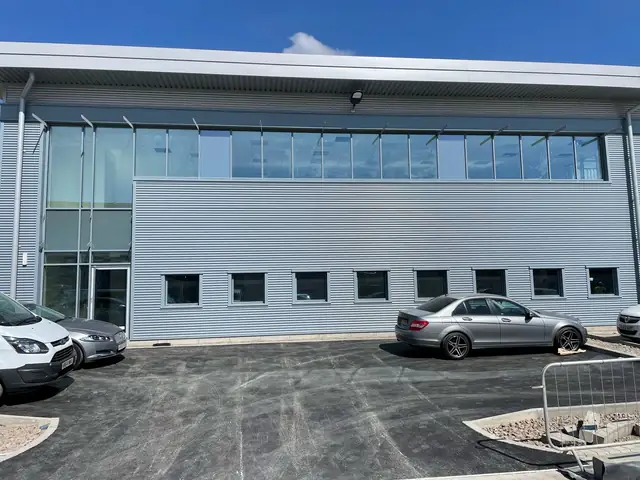 Grey clad industrial unit with a run of aluminium windows and a glazed personnel entrance
