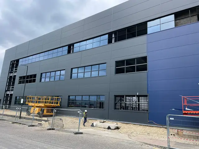 Blue and grey clad commercial building under construction with the aluminium window frames installed