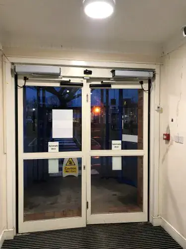 Automatic swing double doors with an overhead operator fitted in a building lobby