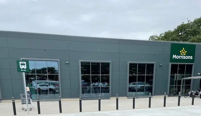 Dark grey supermarket elevation with a run of aluminium windows above the car park