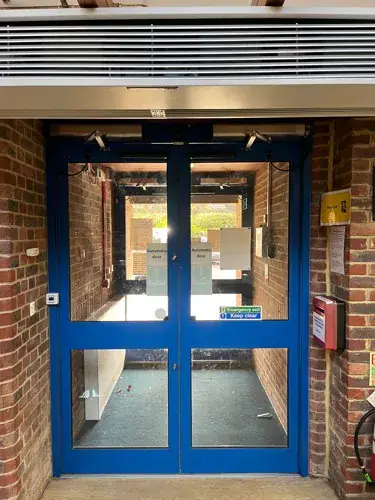 Blue framed double doors with vision panels set into a brick opening