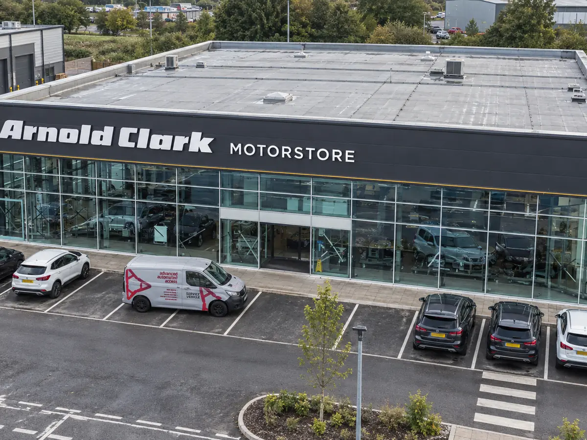 An aerial view of the Arnold Clark Motorstore in Wolverhampton, its full glazed elevation installed by Advanced Automated Access, with a company service vehicle parked outside