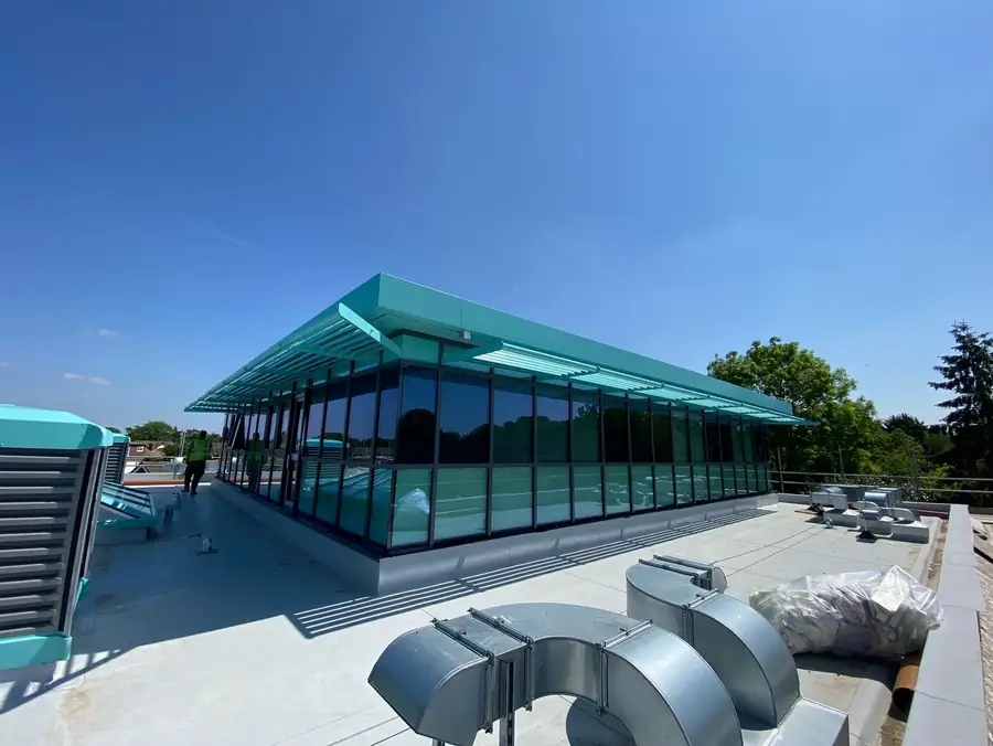 Single storey commercial building glazed in teal tinted curtain walling with plant ductwork on the forecourt